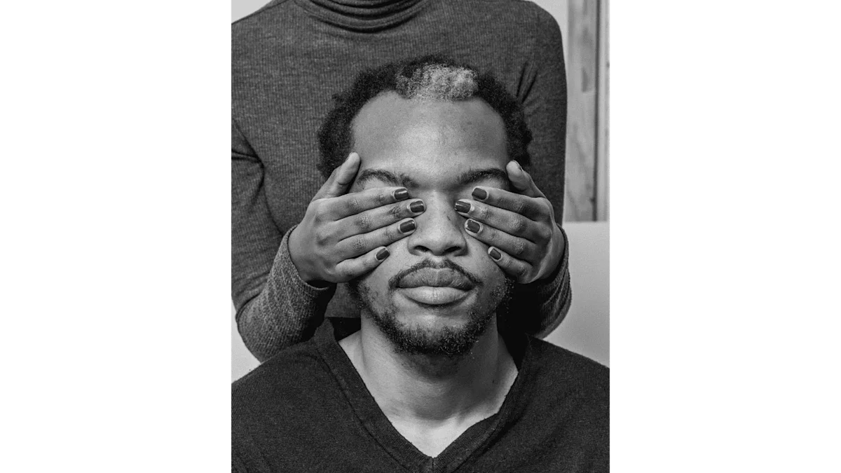 Portrait en noir et blanc d'un homme. Derrière lui se tient une femme qui lui cache les yeux avec ses ongles vernis.