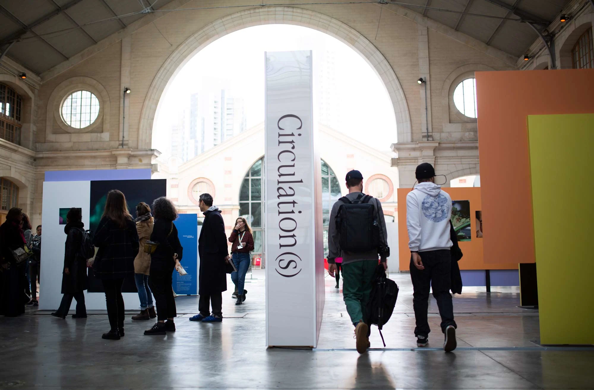 People walk through a large, open hall with high windows. In the middle is a pillar with the inscription “Circulation(s)”.