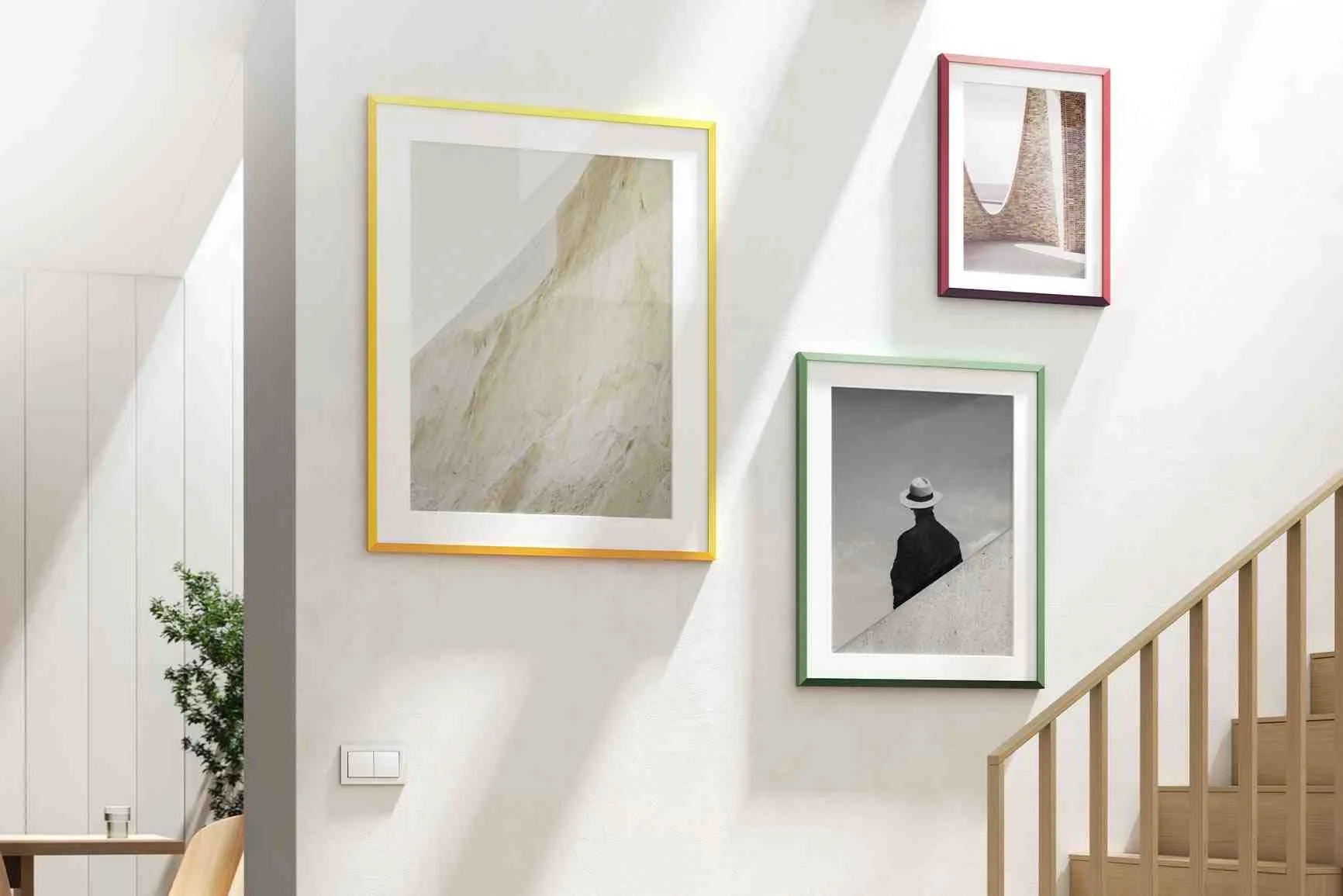 Drei Designrahmen von Studio Besau-Marguerre, einer von jeder Farbe, hängen an einer Wand.