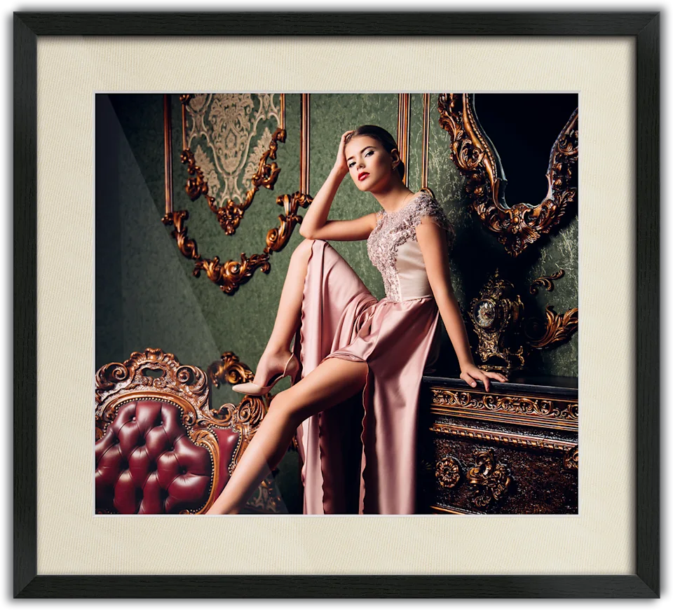 Woman in an elegant pink evening gown sitting on a piece of furniture, passe-partout frame surrounding the photo.