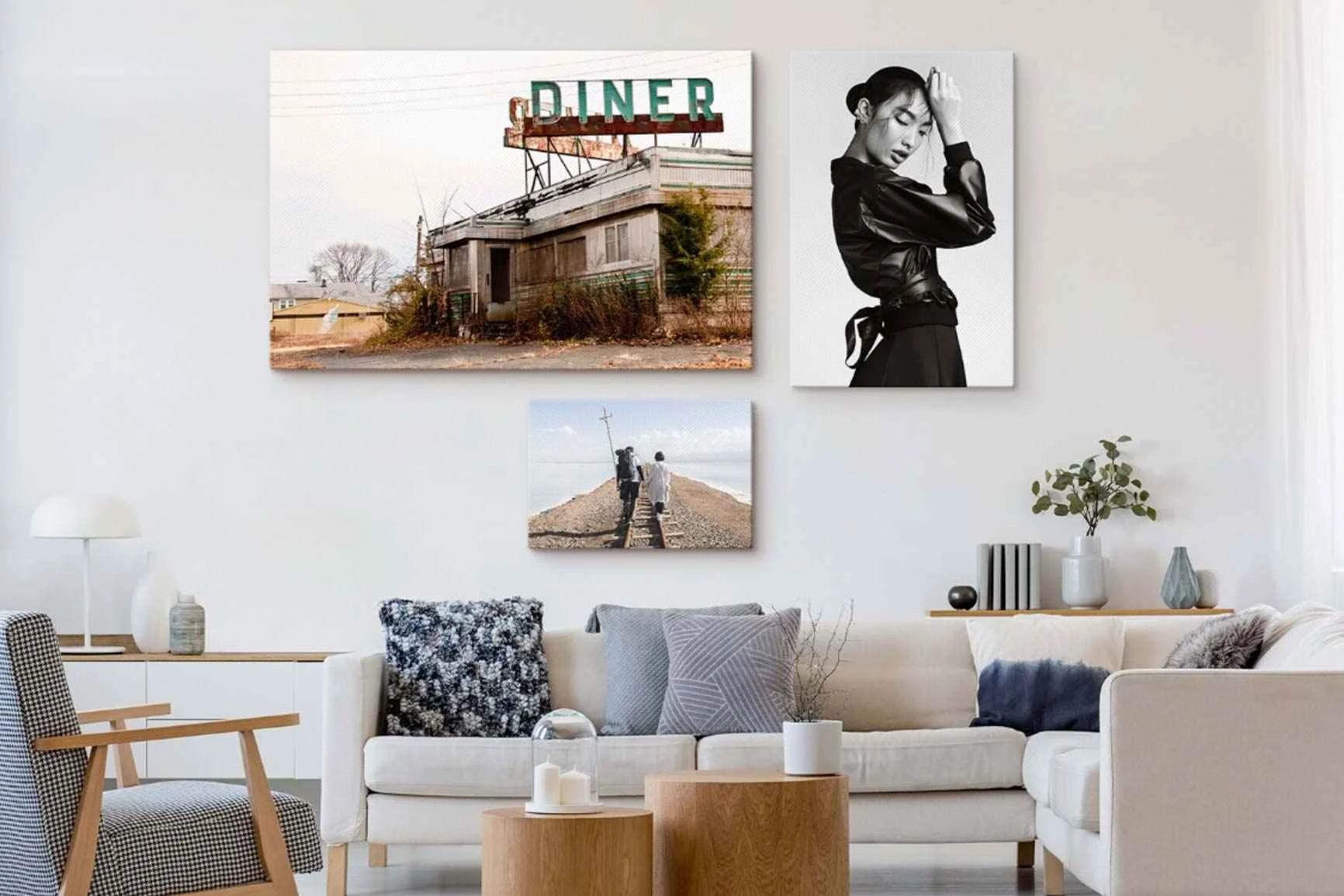 Tre quadri con motivi diversi sopra un divano bianco in un soggiorno.