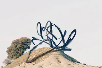 Hill with tree and abstract, black lines in the air against a bright sky. 