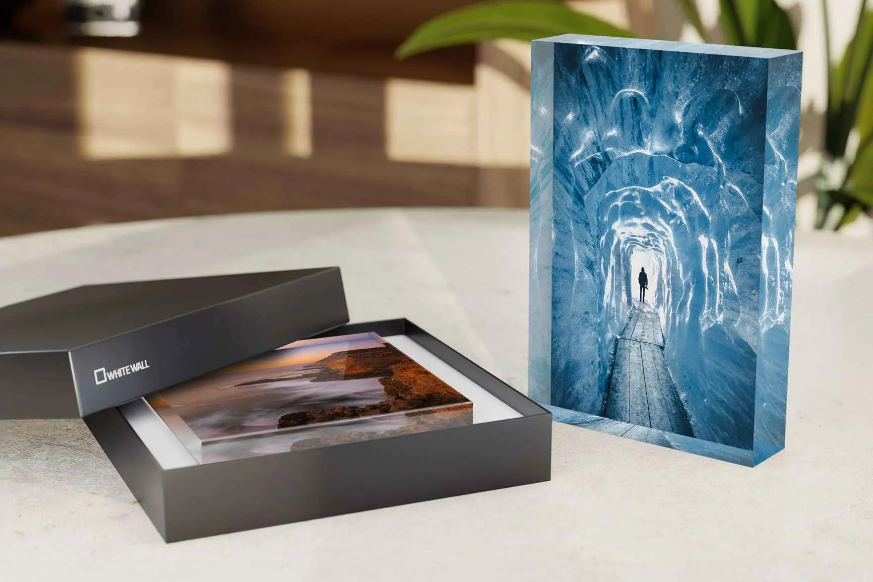 Foto-Acrylblock mit Motiv einer Eishöhle, daneben schwarze Geschenkbox mit offenem Deckel und einem weiteren Acrylblock mit Landschaftsbild.
