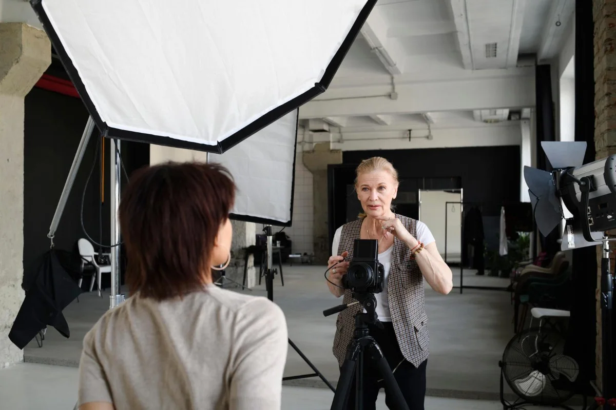 Photo studio with professional lighting and camera on a tripod, two people during a photo shoot.