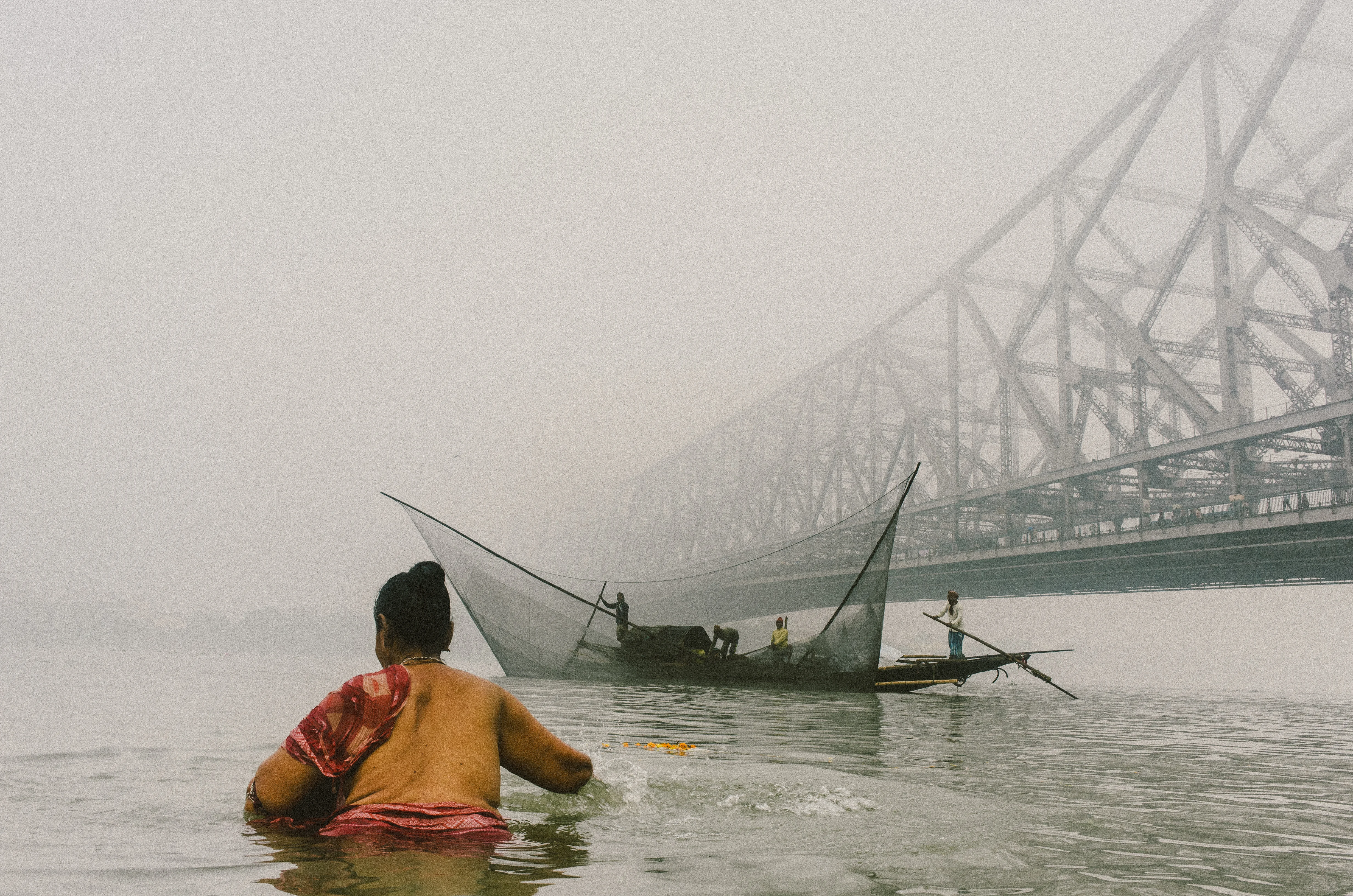 woman standing in water with a fisher boat in the background.