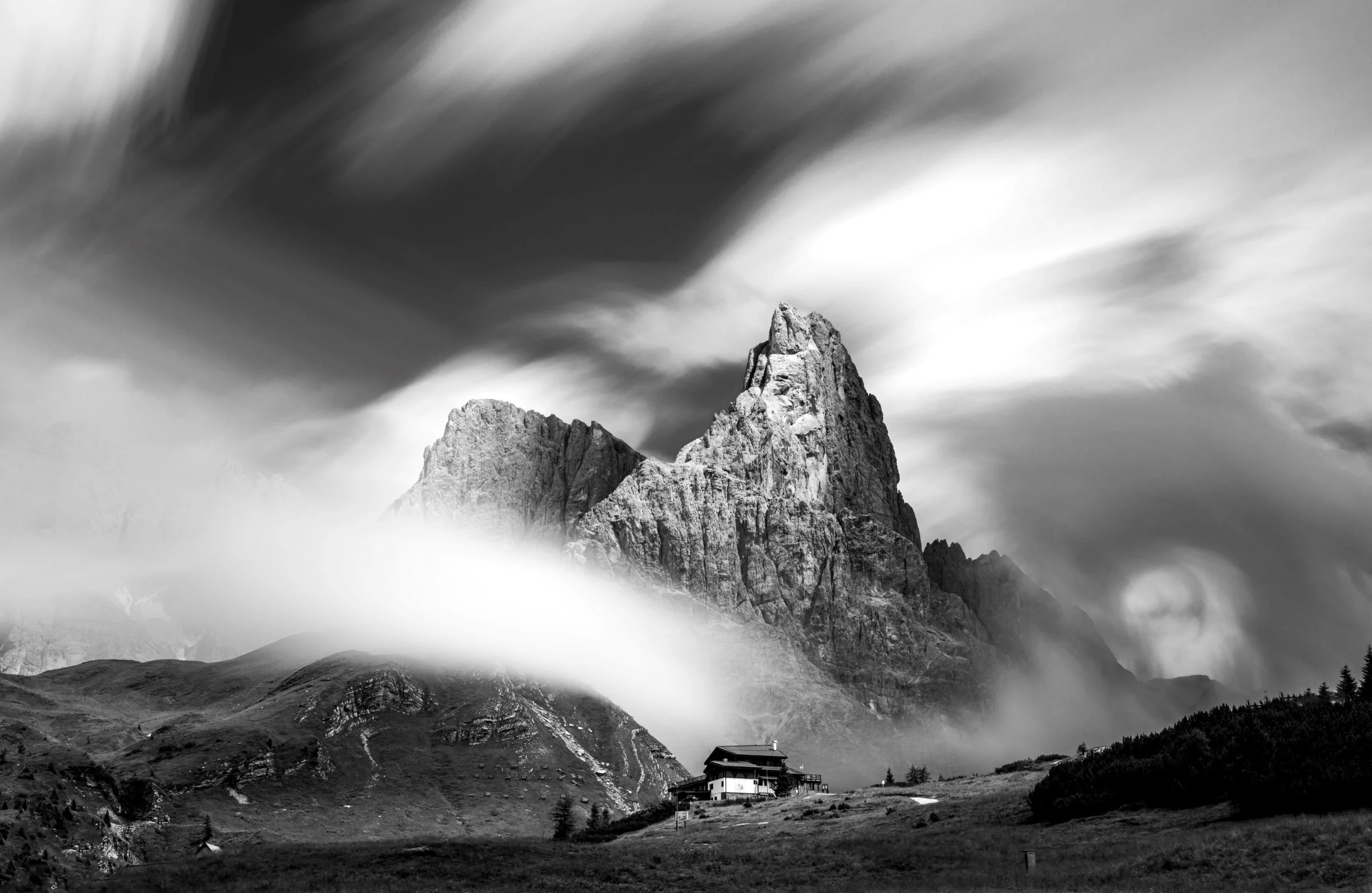 Une longue exposition montre un sommet de montagne dans les Dolomites, entouré de nuages en mouvement, prise en noir et blanc par Stephan Wiesner.