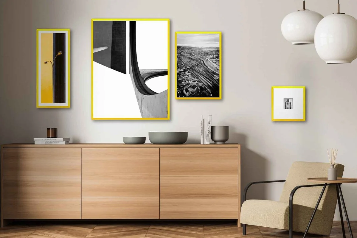 Soggiorno con quattro fotografie incorniciate con cornici gialle della WhiteWall Design Edition by Studio Besau-Marguerre appese alla parete.