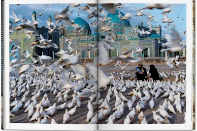 Steve McCurry - Masar-­e Scharif, 1991, Dozens of pigeons fly around two people in the square in front of Hazrat Ali Mazar mosque.