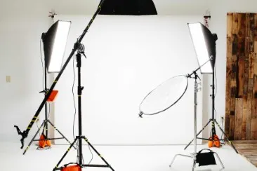 Photo studio with two large softbox lights, a reflector, and a white background.