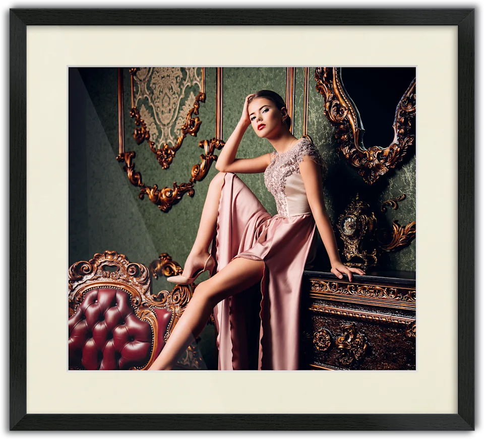 Woman in an elegant pink evening gown sitting on a piece of furniture, passe-partout frame surrounding the photo.