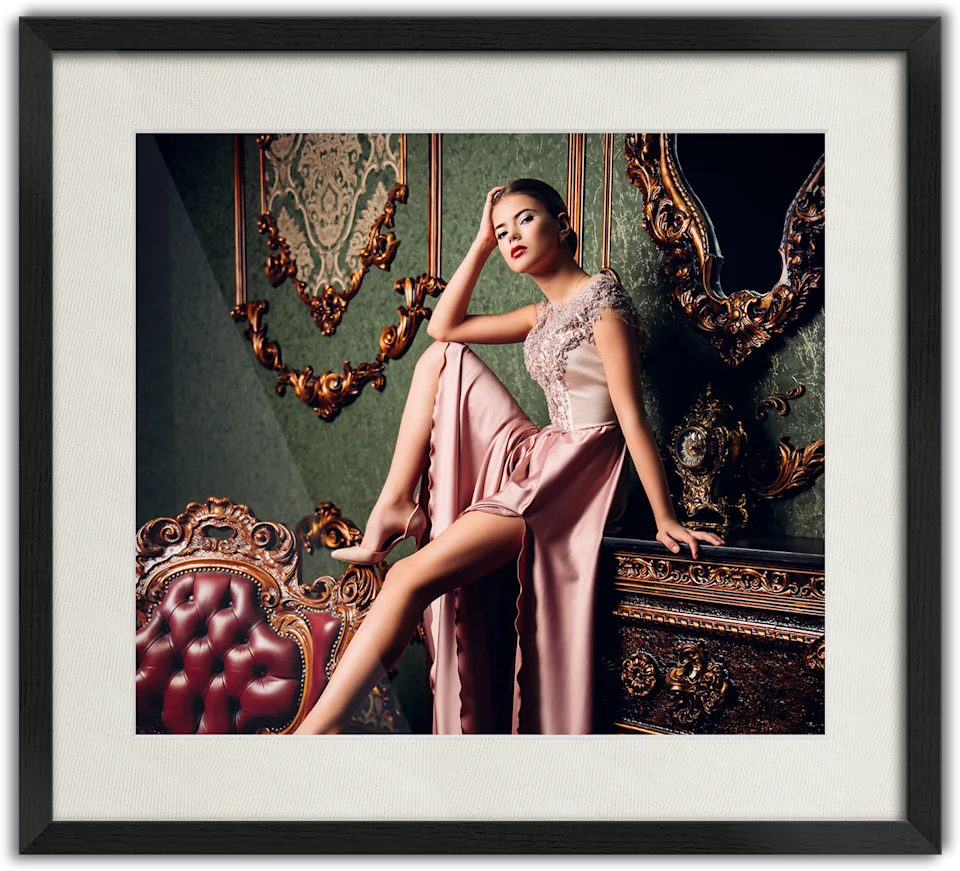 Woman in an elegant pink evening gown sitting on a piece of furniture, passe-partout frame surrounding the photo.