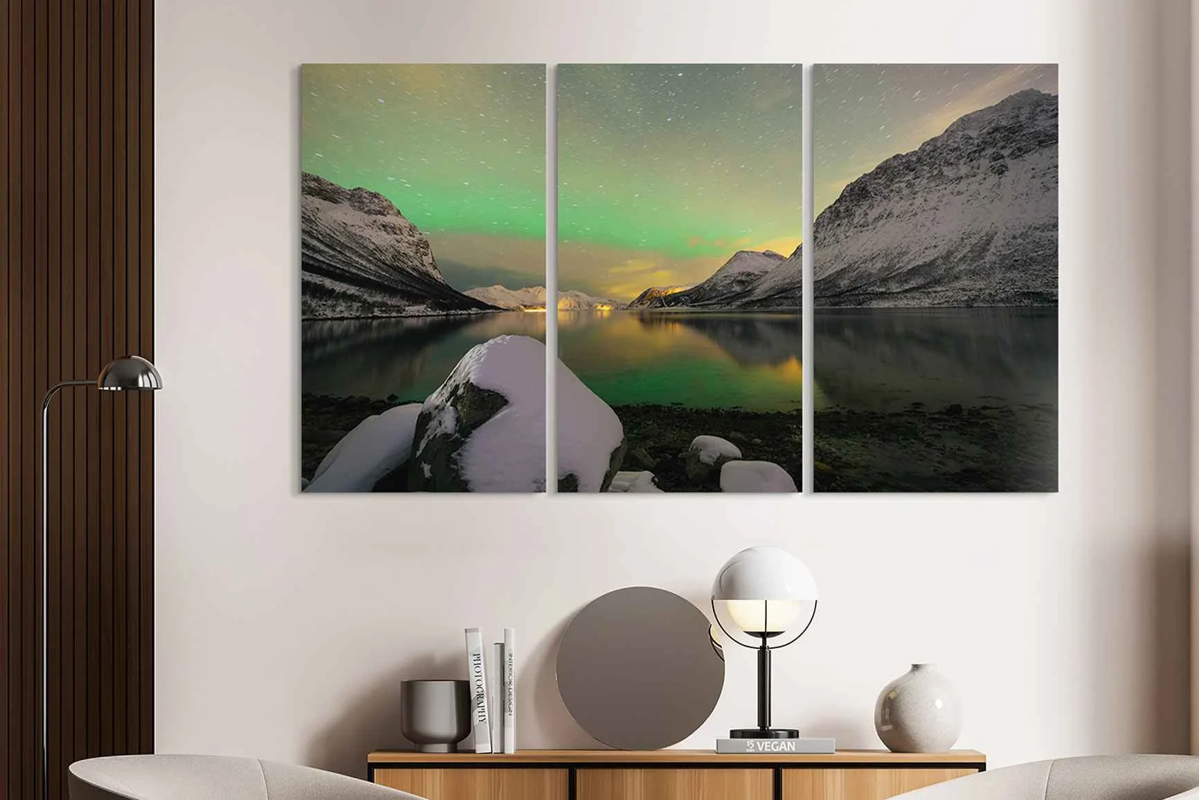 Pannello murale in tre parti con paesaggio montano invernale e aurora boreale verde sopra un lago tranquillo in un appartamento moderno.