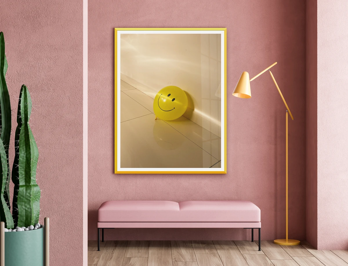 Ambience image of a framed photograph with yellow Design Edition frame and a yellow balloon with a smiley face.