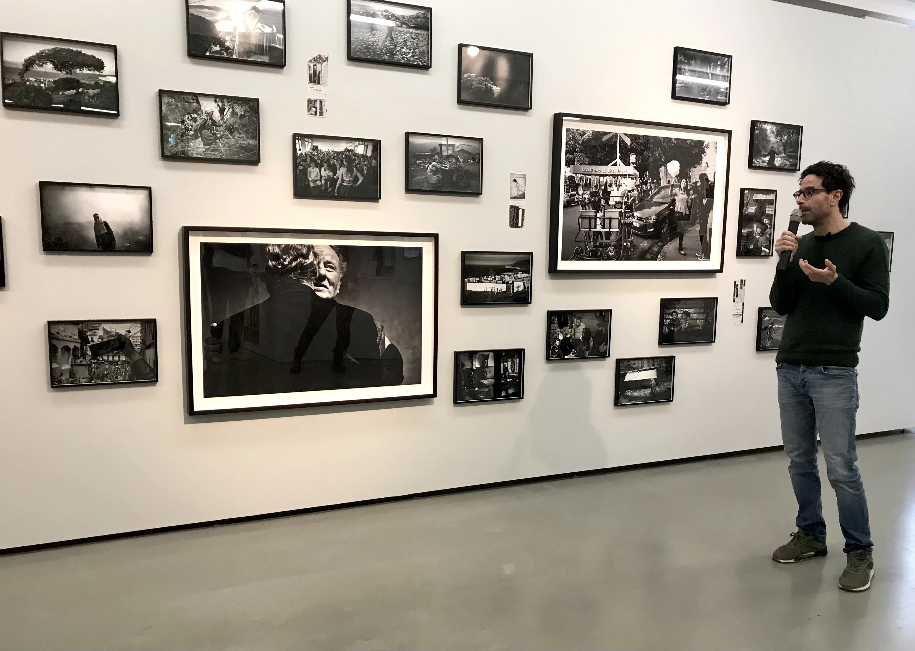 Ferhat Bouda standing in front of his photo prints hanging on the exhibition wall.