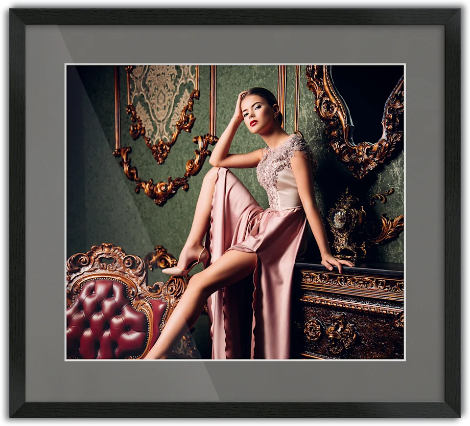 Woman in an elegant pink evening gown sitting on a piece of furniture, passe-partout frame surrounding the photo.