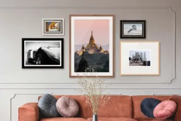 Verschiedene gerahmte Fotografien an einer Wand über einem Sofa.