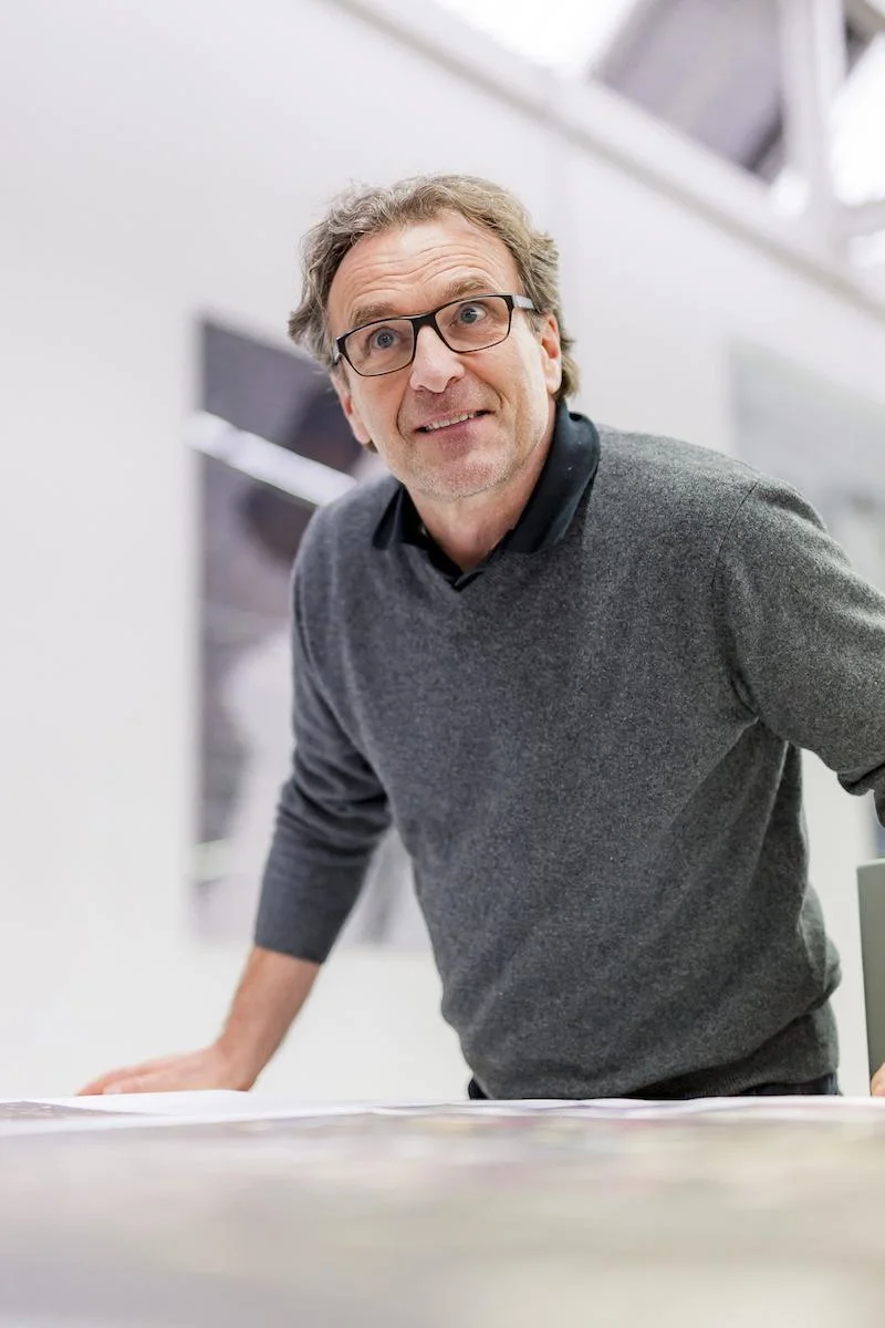 Mann mit Brille und grauem Pullover lehnt sich nach vorne.