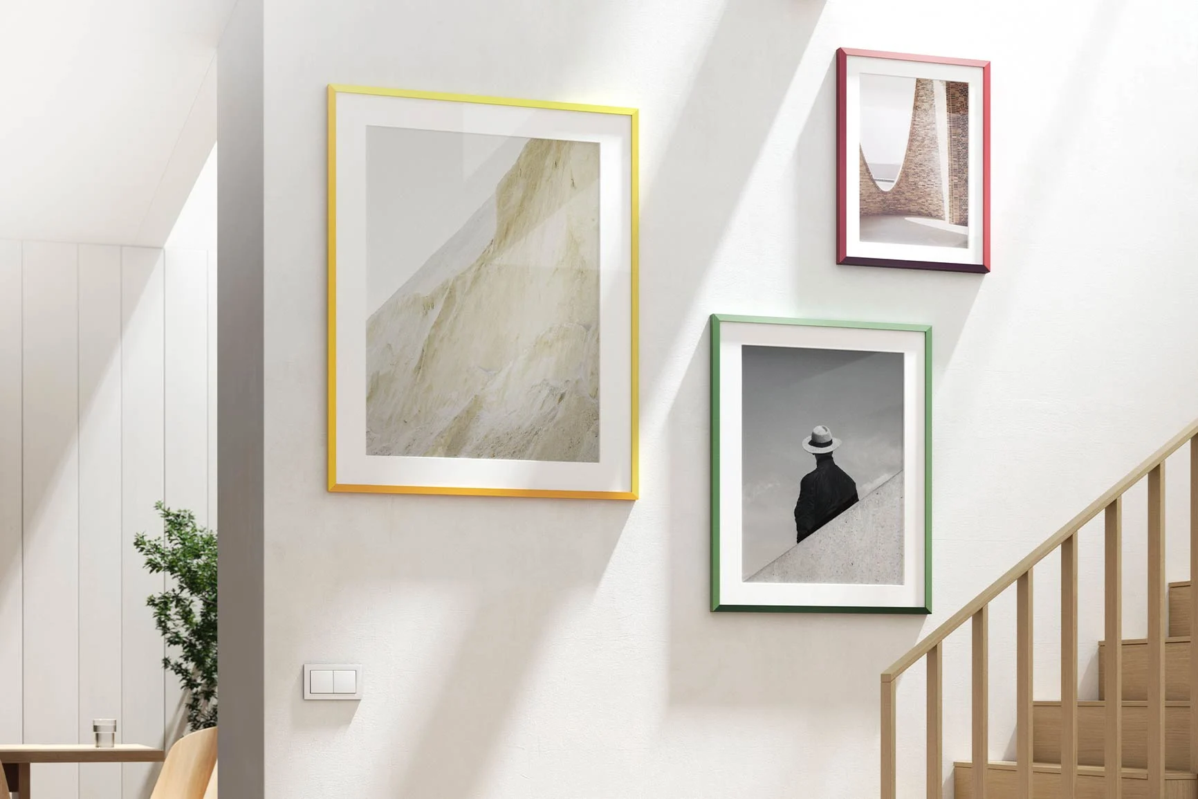 Drei Designrahmen von Studio Besau-Marguerre, einer vonjeder Farbe, hängen an der Wand.