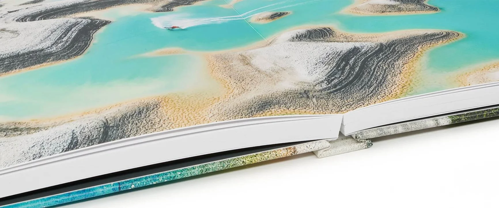 Aufgeschlagenes Buch mit einer Ansicht von Wasser und Sandstränden.