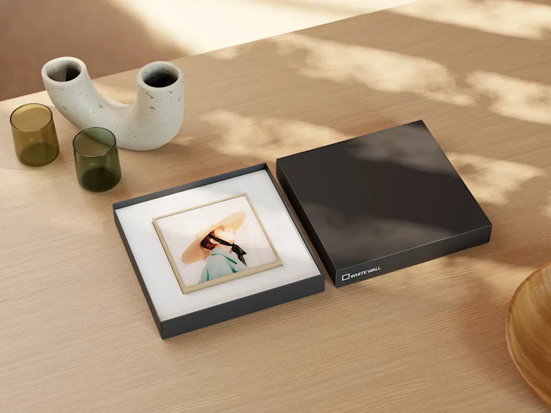 ArtBox with a portrait of a woman wearing a straw hat, lying in a gift box on a wooden table.
