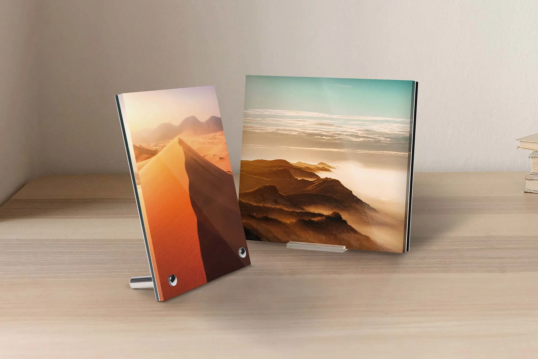 Zwei Fotoaufsteller aus Acrylglas mit Landschaftsbildern, einer zeigt eine Wüstenlandschaft mit Sanddünen, der andere Berge mit Wolken.