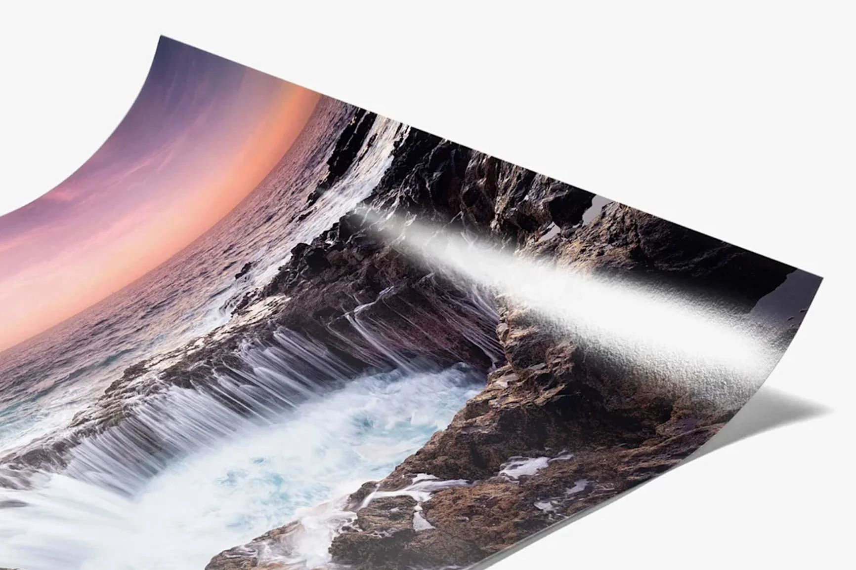 Ein gedrucktes Bild zeigt eine Küstenlandschaft mit Wellen, die gegen Felsen schlagen.