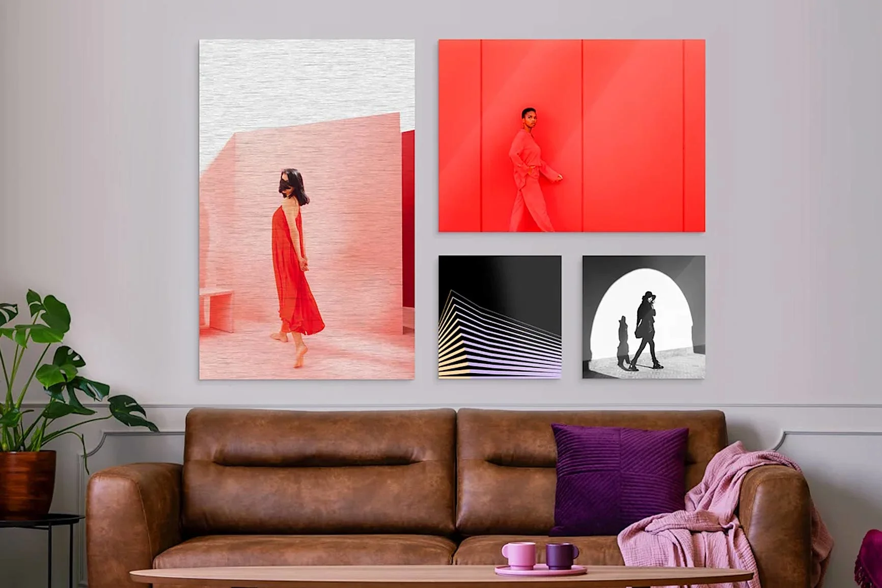 Vier Bilder vor einer Wand über braunen Sofa, zwei davon in rötlichen und zwei in dunklen Farben.