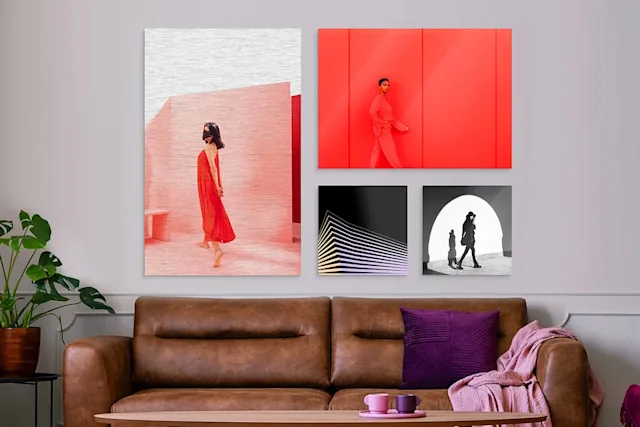 Vier Bilder vor einer Wand über braunen Sofa, zwei davon in rötlichen und zwei in dunklen Farben.