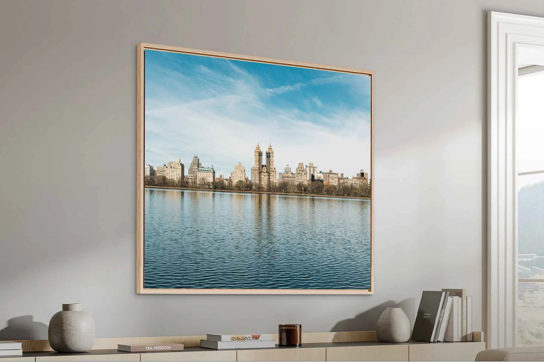 Foto di un paesaggio urbano con grattacieli e acqua in primo piano in una cornice a cassetta con effetto ombra su una parete chiara.