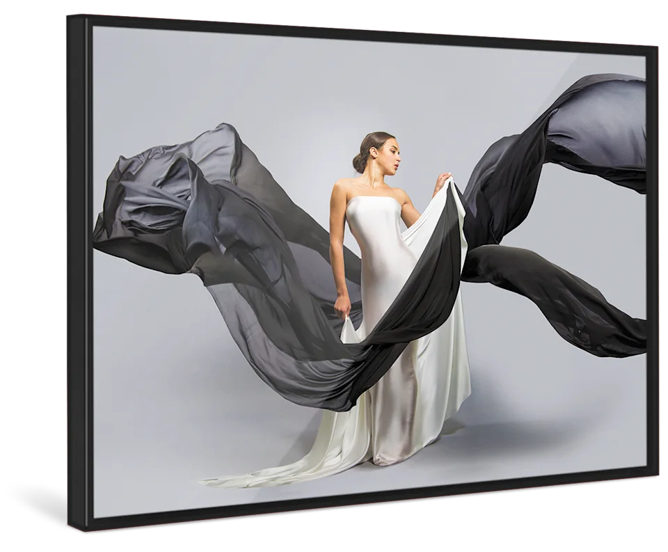 A woman in a white wedding dress holds black linen flying through the picture in a black Pop Art Frame.