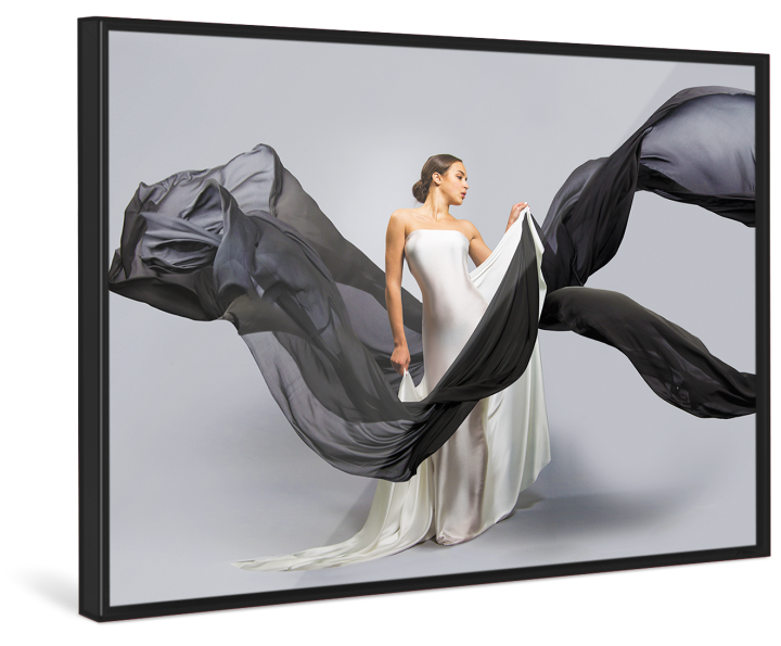 A woman in a white wedding dress holds black linen flying through the picture in a black Pop Art Frame.