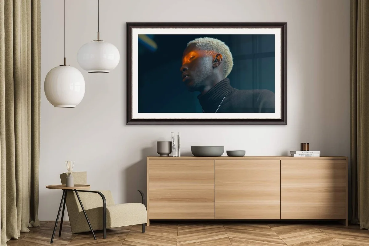 Moderner Wohnraum mit Holzsideboard, Sessel, zwei hängenden Lampen und einem gerahmten Porträt an der Wand.