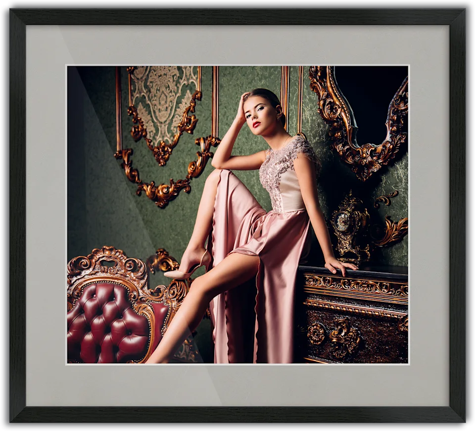 Woman in an elegant pink evening gown sitting on a piece of furniture, passe-partout frame surrounding the photo.