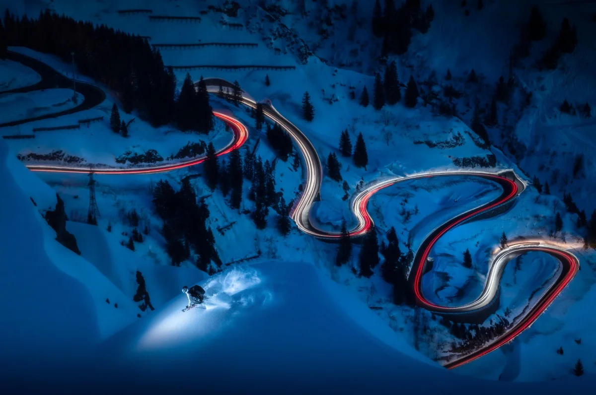 mountain range with skier, night scene, illuminated serpentine.