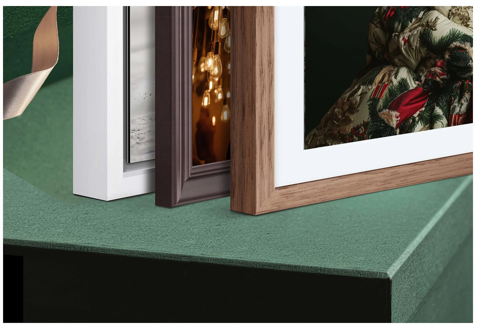 Three framed prints standing on a green gift box. We see just the edges with the structure of the wood. 