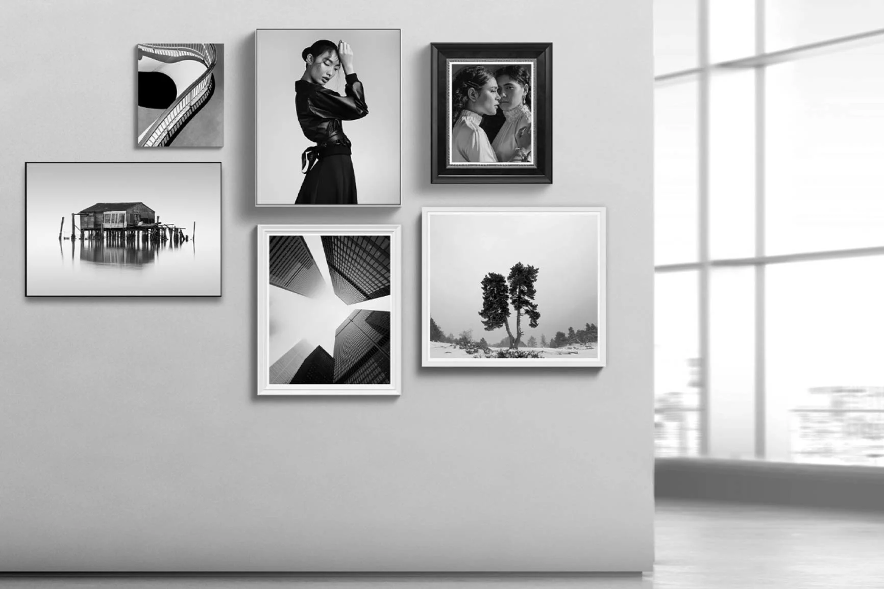 Sei fotografie in bianco e nero su una parete bianca, tra cui ritratti, paesaggi e fotografie astratte incorniciate.