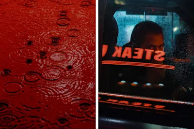 Red water surface on the left, “STEAK” lettering reflected in car windshield on the right, person behind.