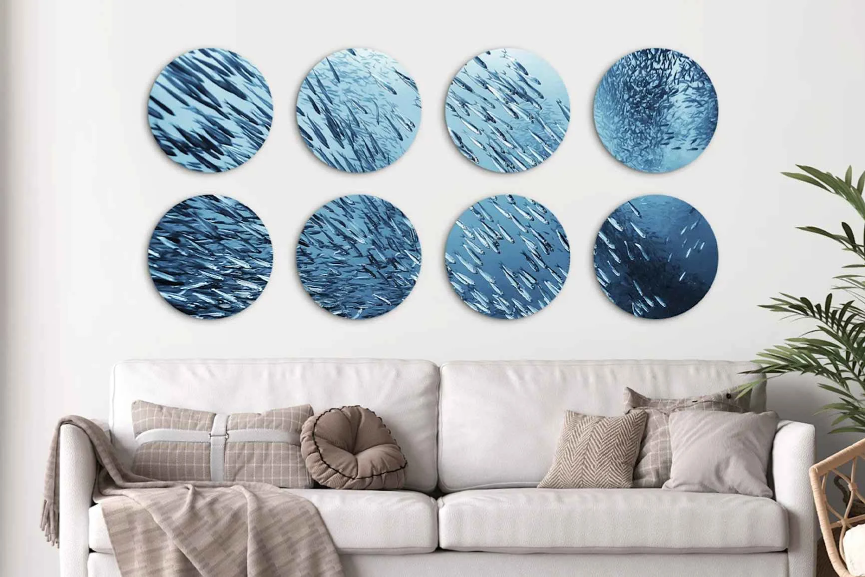 Otto foto rotonde con motivi di pesci sopra un divano chiaro con cuscini e coperta.