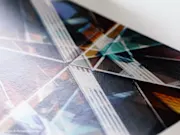 Nahaufnahme eines Fine-Art-Prints mit geometrischen Linien und Formen in Türkis, Orange und dunklen Farbtönen auf strukturiertem Papier.