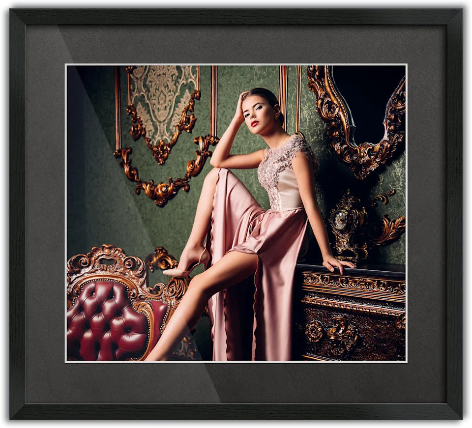 Woman in an elegant pink evening gown sitting on a piece of furniture, passe-partout frame surrounding the photo.