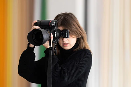 Mary Ruffinoni holding a camera at the viewer.