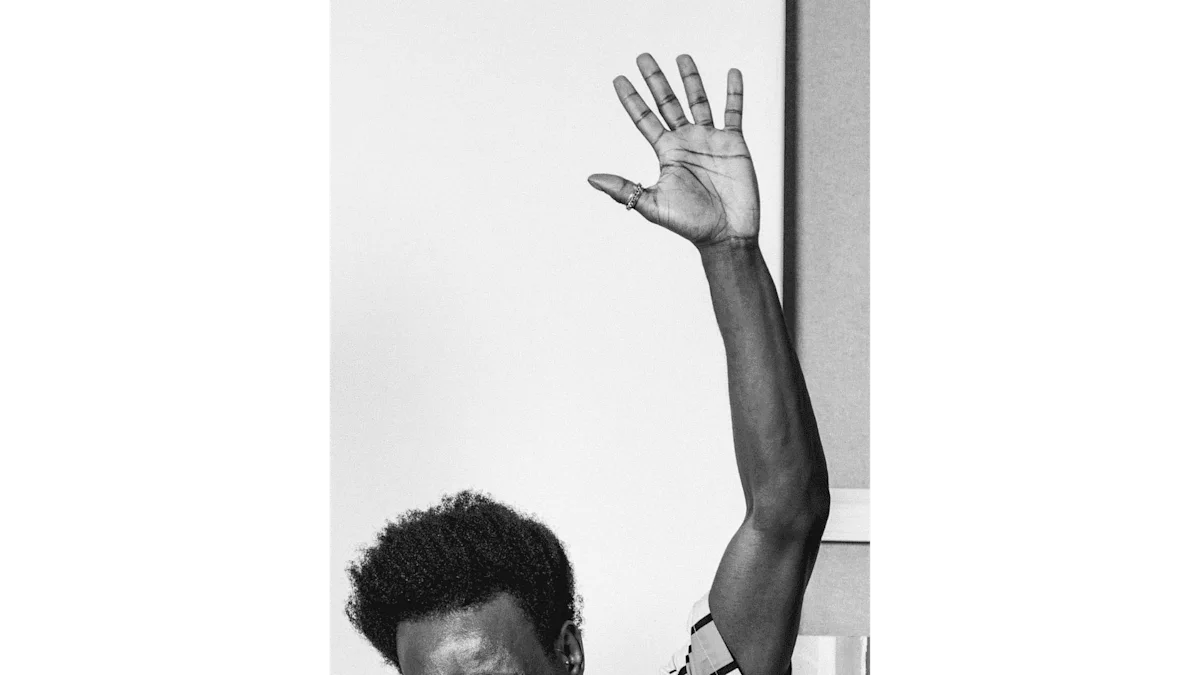 Photo en noir et blanc d'un homme. On ne voit que son front et ses cheveux. Il lève une main en l'air.