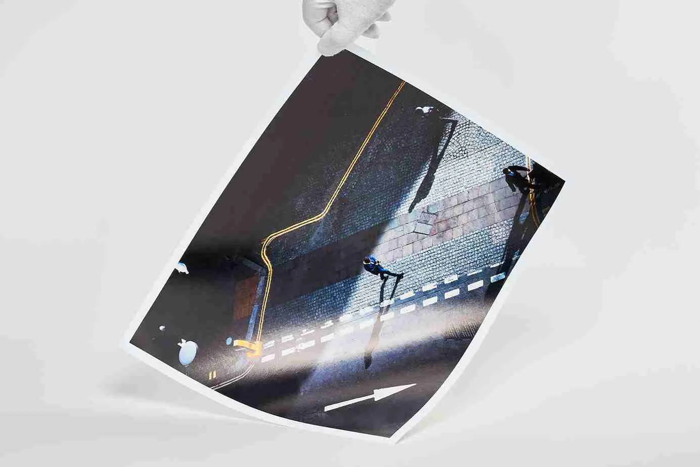 Fine Art Print zeigt eine Vogelperspektive auf eine Straße mit Zebrastreifen, gelber Linie und Pfeilmarkierung, gehalten von einer Hand.