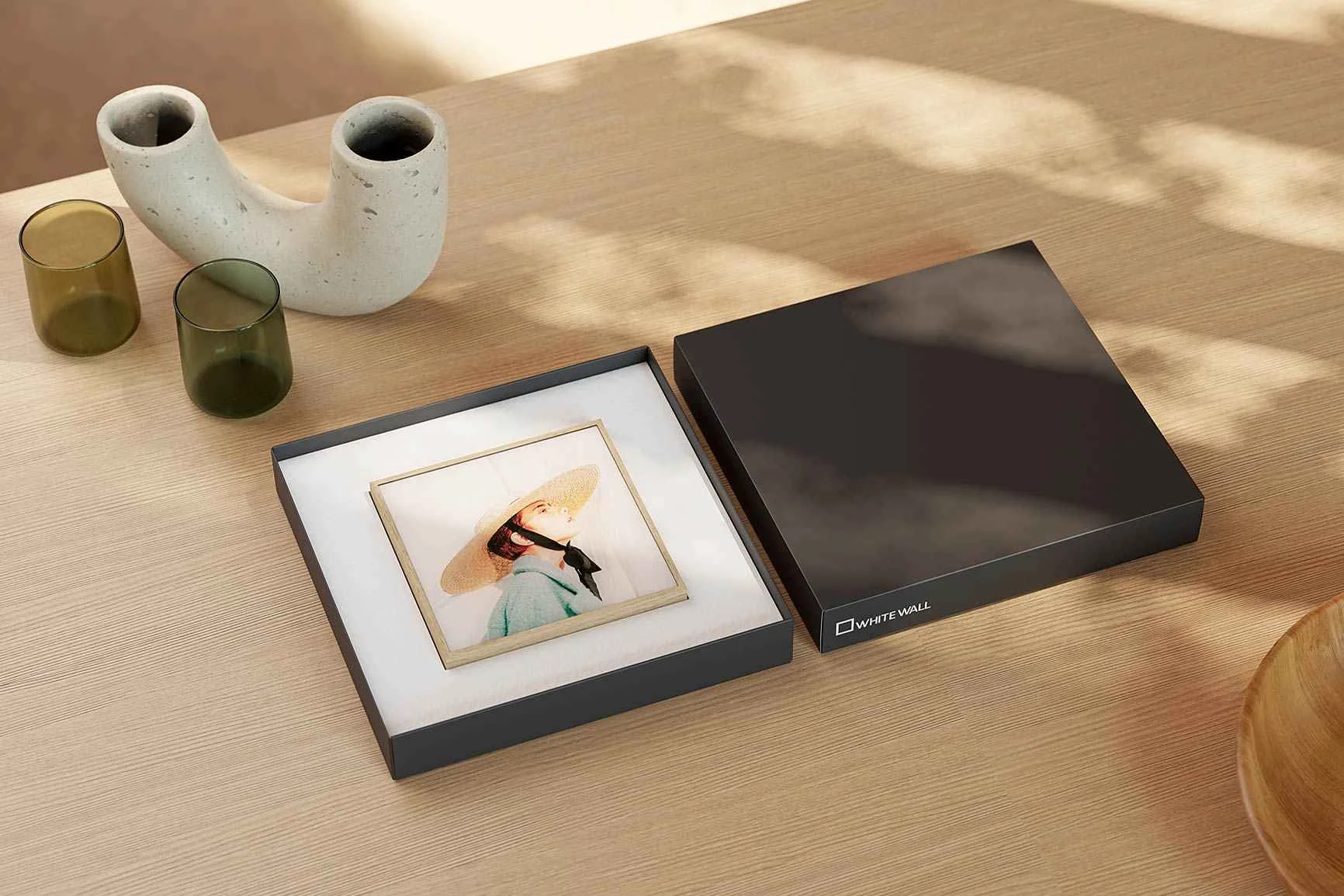 ArtBox mit dem Portrait einer Frau mit Strohhut, die in einer Geschenkbox auf einem Holztisch liegt.