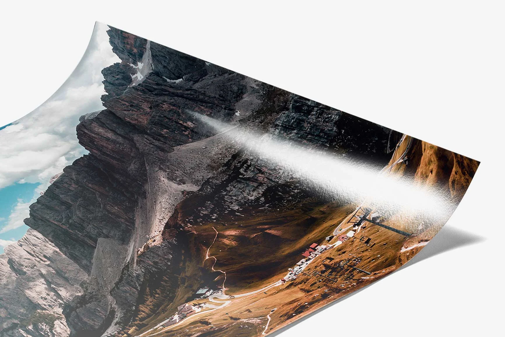 Eine Fotografie zeigt eine Berglandschaft mit Felsen und einem Tal, das von einer Straße durchzogen ist.