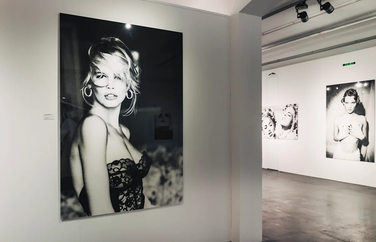 Large black and white fashion photographs displayed in a modern gallery space with white walls and concrete floors