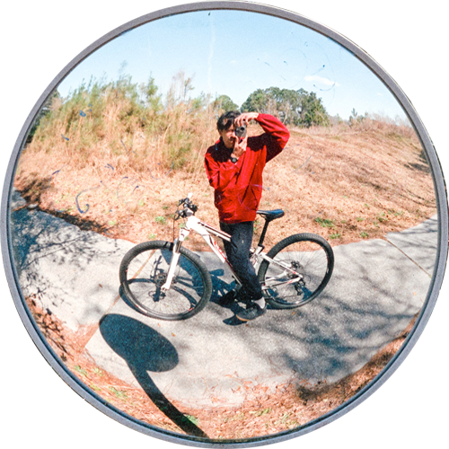 curved mirror portrait of Colin Czerwinski on a bike.