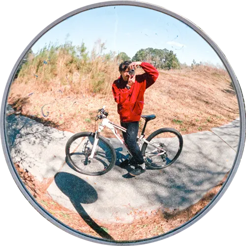 curved mirror portrait of Colin Czerwinski on a bike.