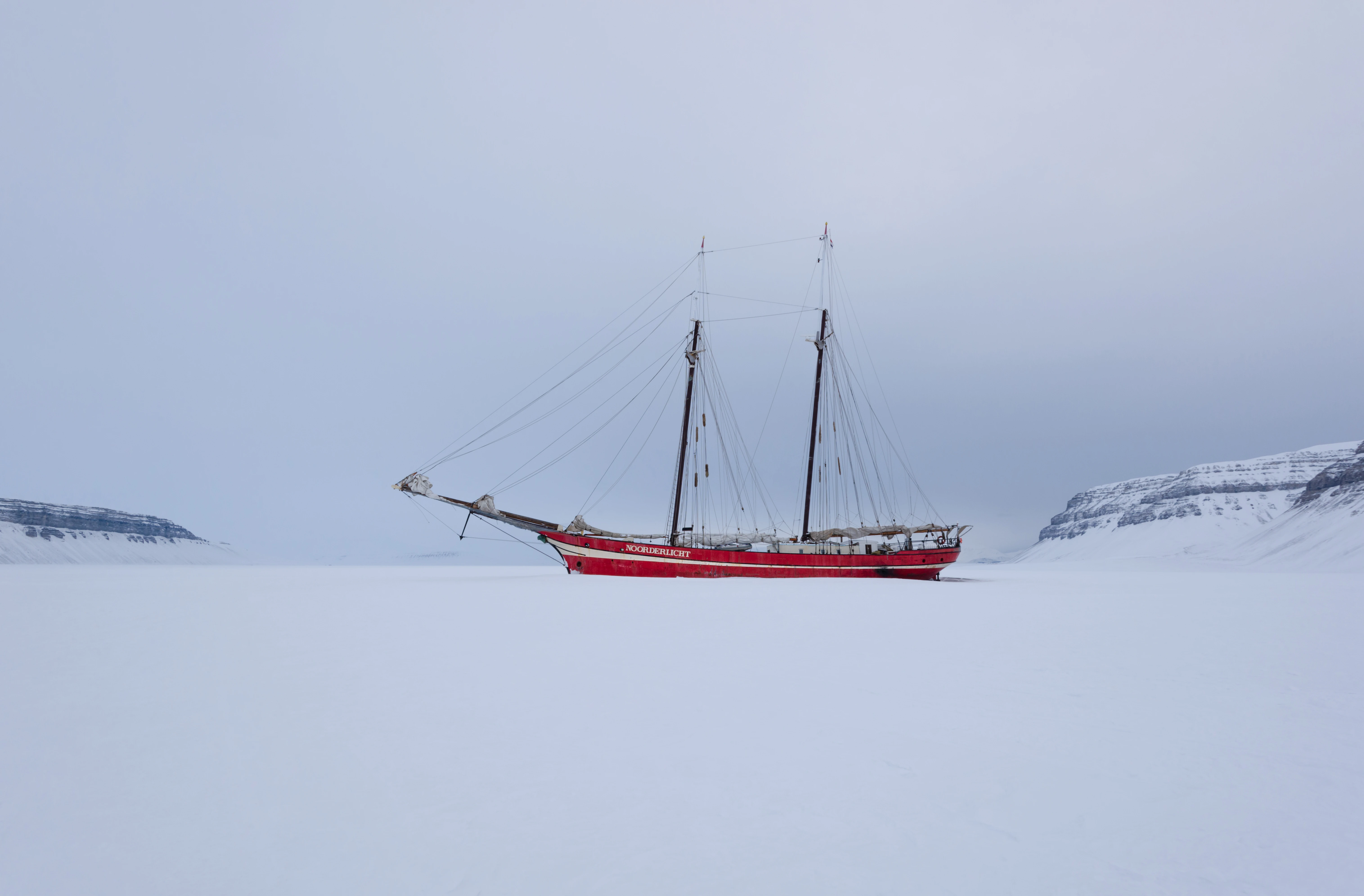 Red ship sailing in icy waters.