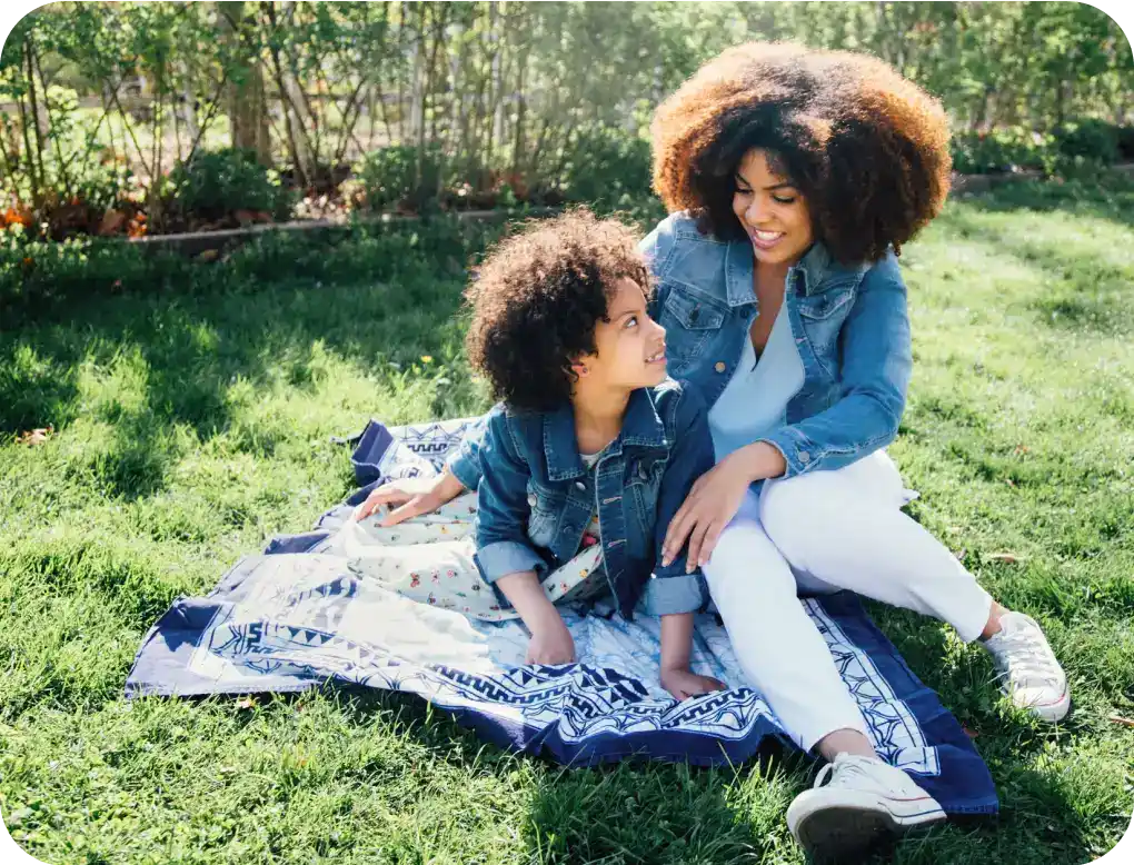 Woman and girl sitting on grass field